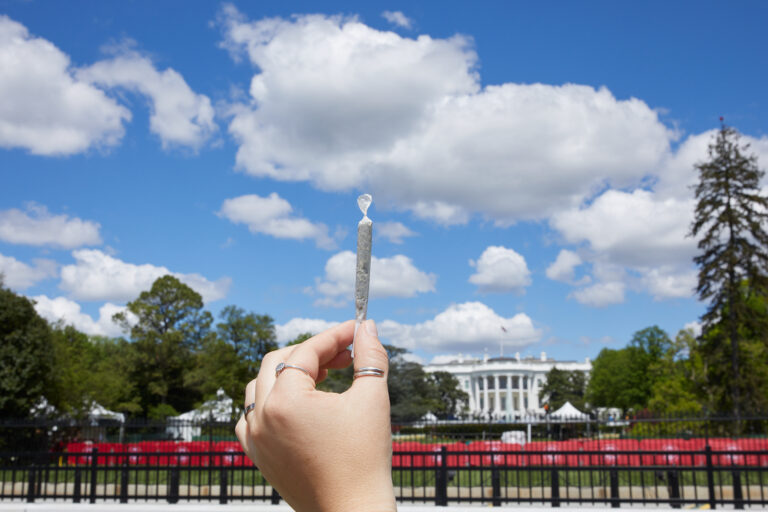 Hand holding a joint in front of White House