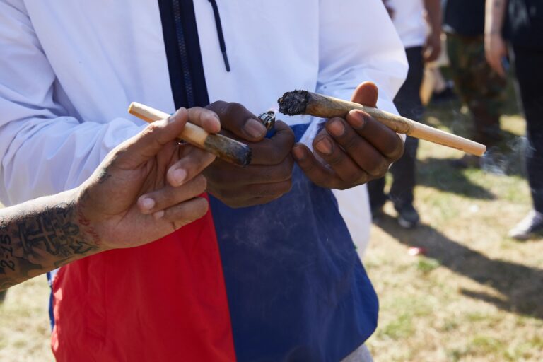 Hands passing giant joints at festival