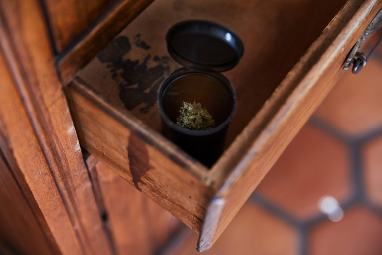 Cannabis in black container stored in a drawer.
