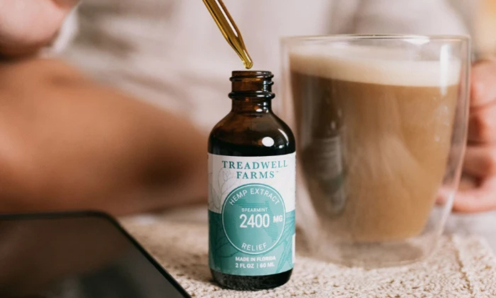 A bottle of Treadwell Farms hemp extract beside a beverage